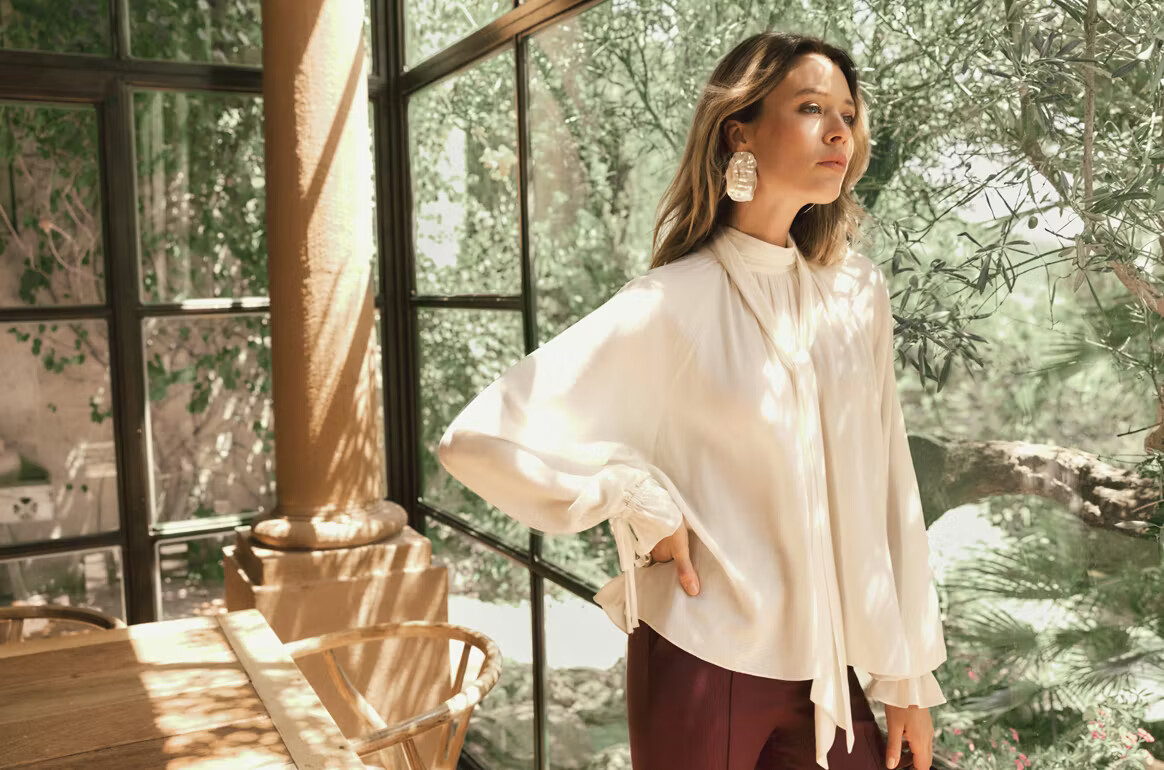 Modelka w jasnej bluzce z wiązaniem i bordowych spodniach: MAKALU The Art of Her